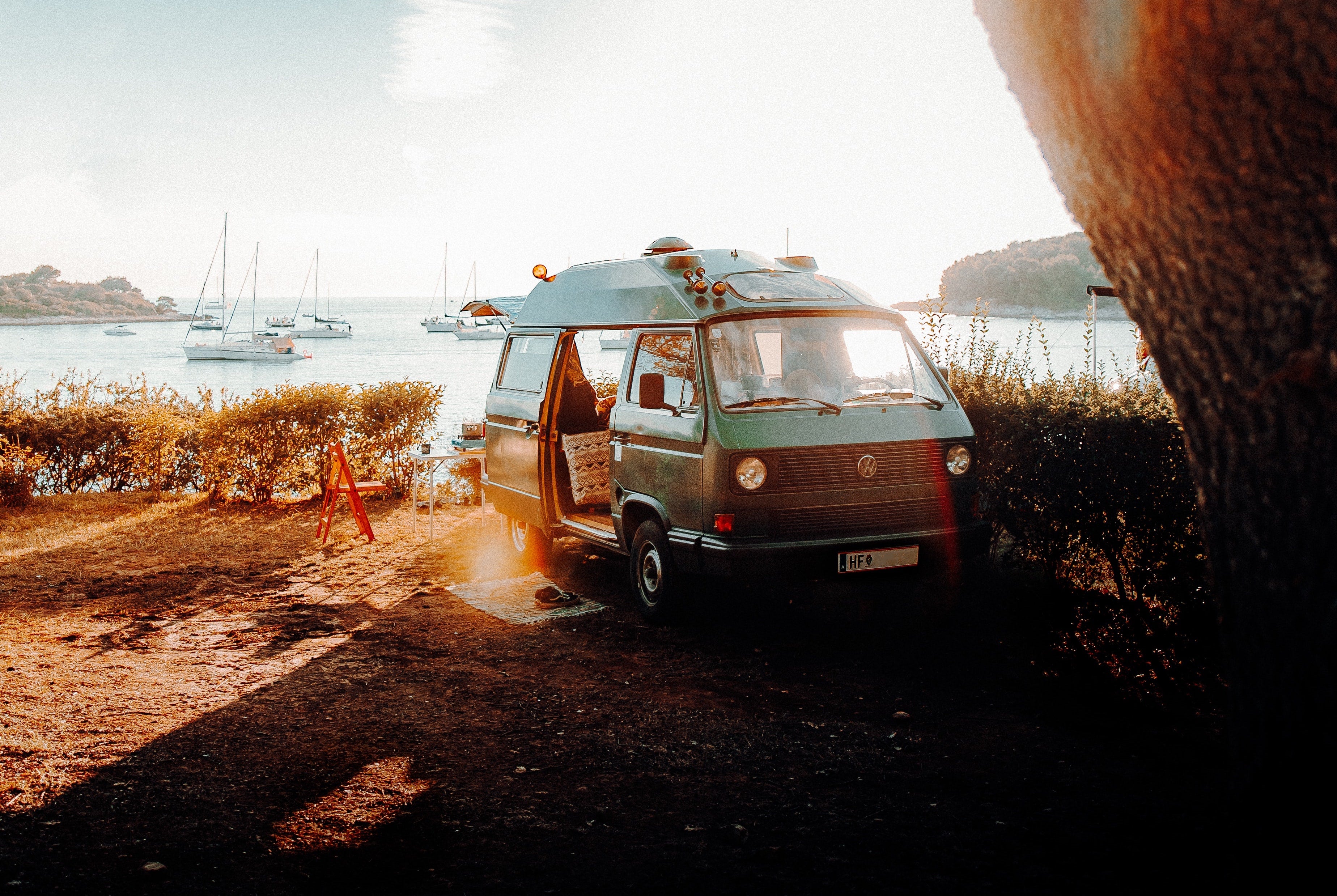 Foto eines Vans am See, mit offener Tür - Photo by Daniel J. Schwarz, Unsplash